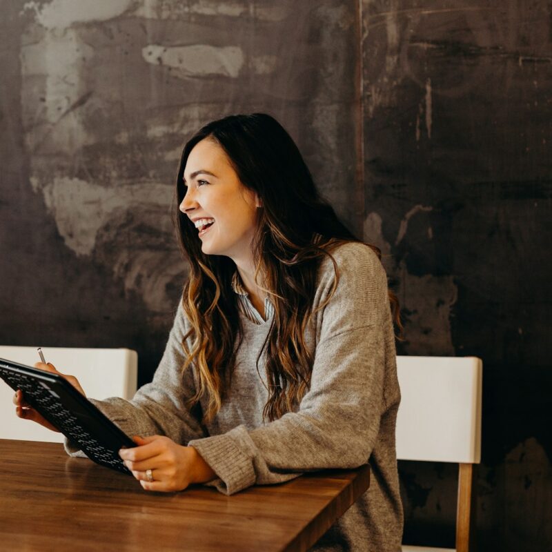 woman sitting around table holding tablet